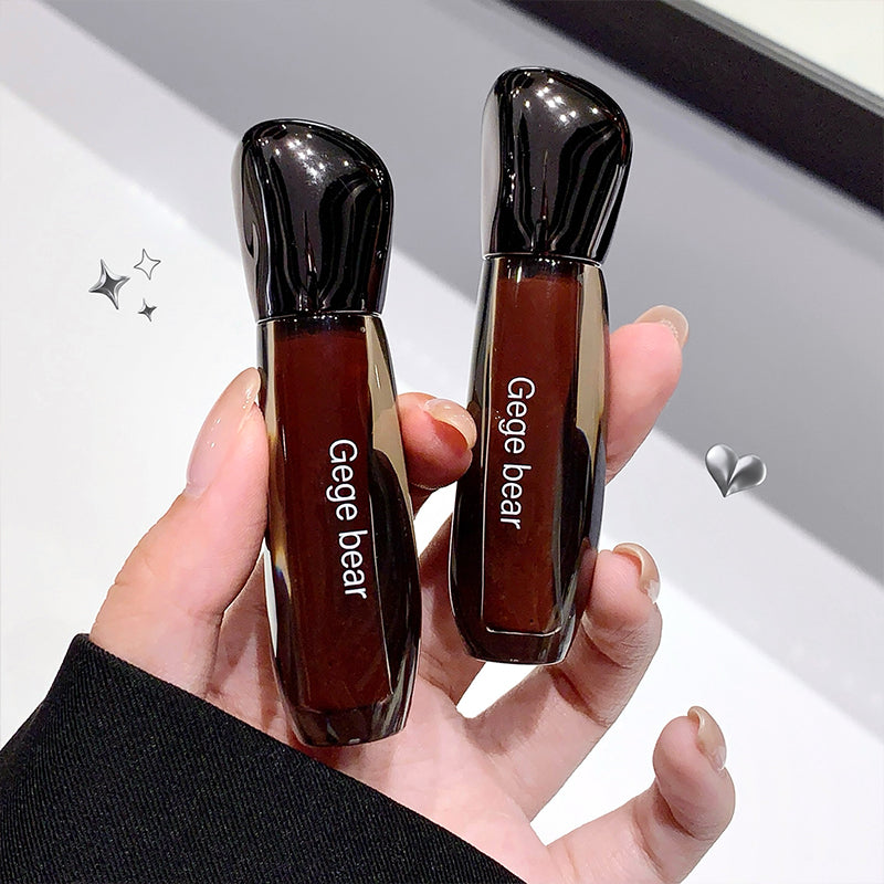 Two lip glosses with 'Gege bear' branding held in a hand against a neutral background.