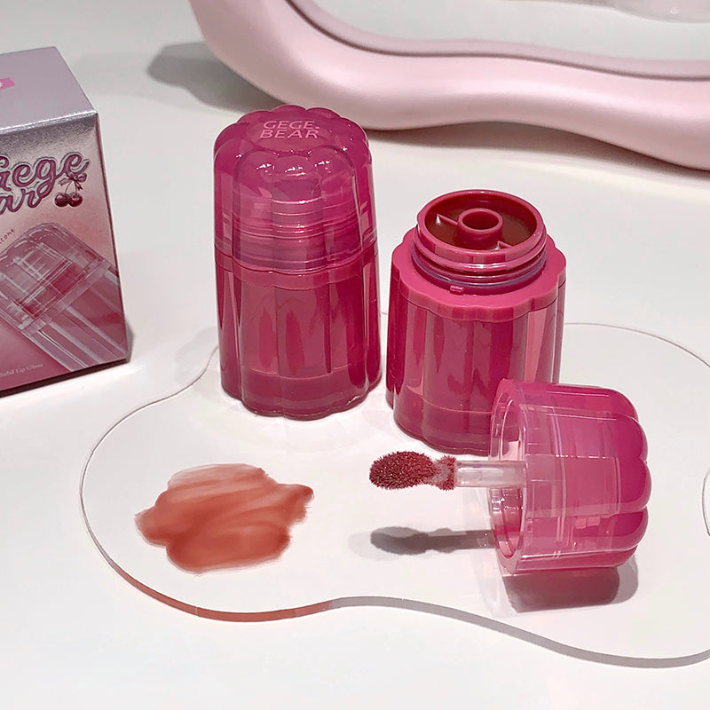Pink lip gloss with applicator and packaging on a white surface