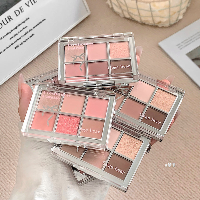 Makeup palettes with 'Gige bear' branding on a beige surface