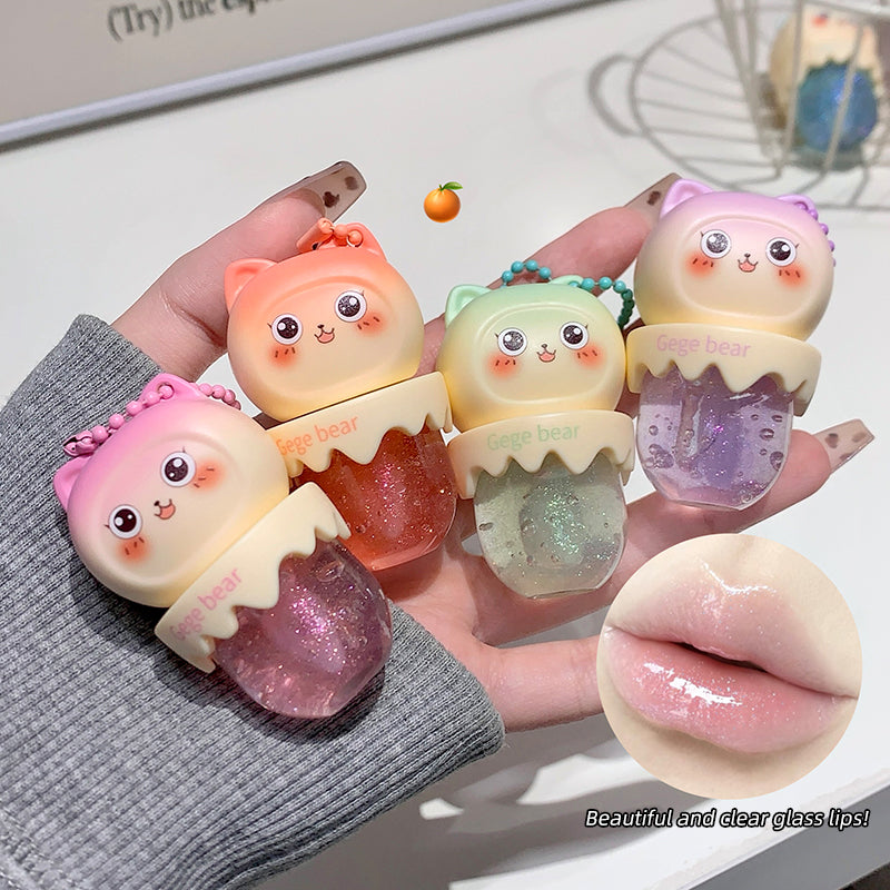 Hand holding four small, colorful lip gloss containers with cartoon designs on a light background.