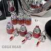 Red nail polish bottles with silver caps and applicators on a white surface, branded 'GEGE BEAR'.