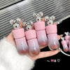 Set of pink gradient lip balms with silver tops held by a hand against a metallic background.