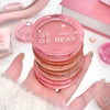 Pink GE BEAR blush container held in a hand with a blurred background