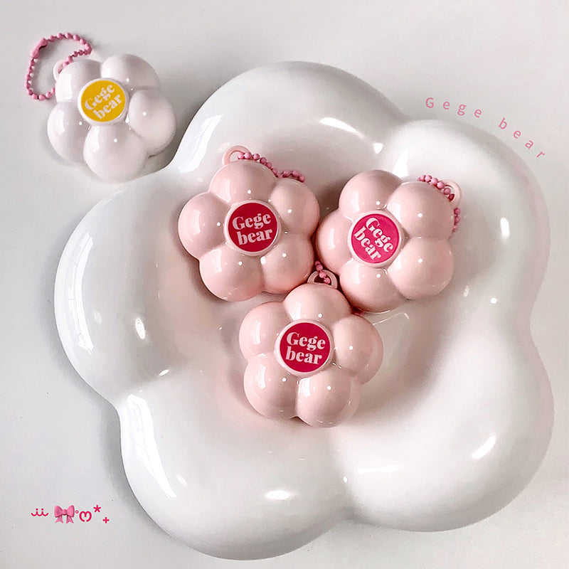 Pink 'Gege bear' products on a white cloud-shaped stand with a small pink keychain in the background.
