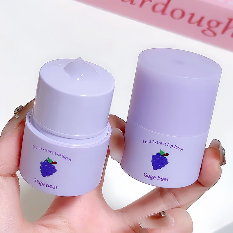Two purple lip balm containers held by a hand with a blurred background