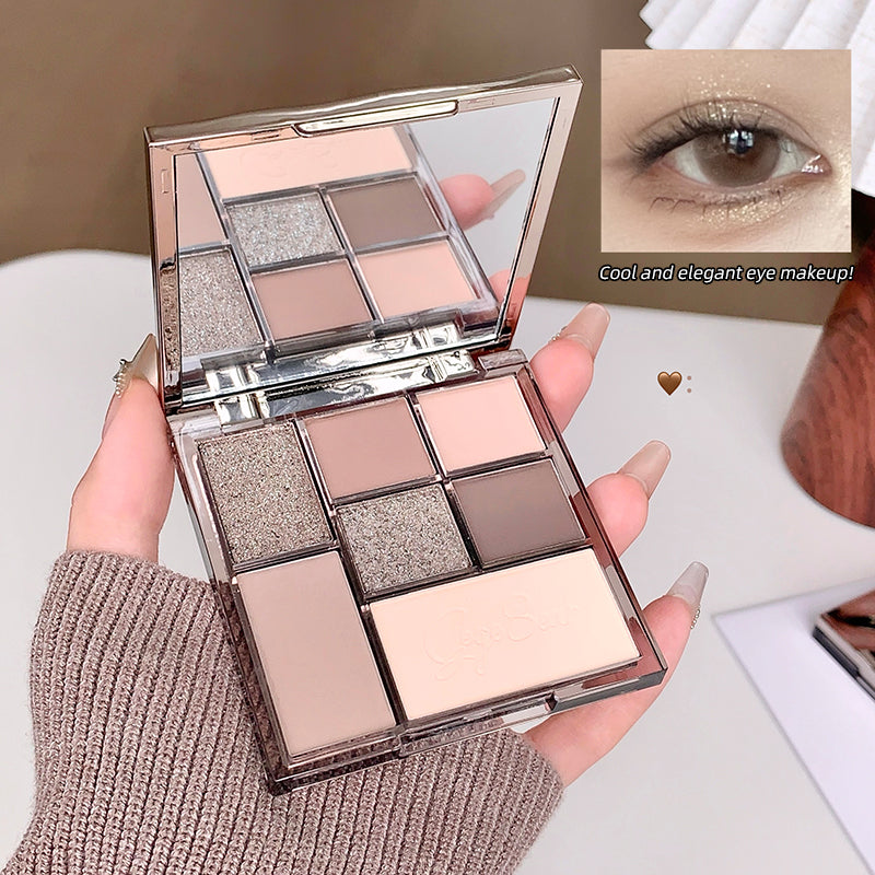 Makeup palette with six colors held by a hand, close-up of eye makeup application.