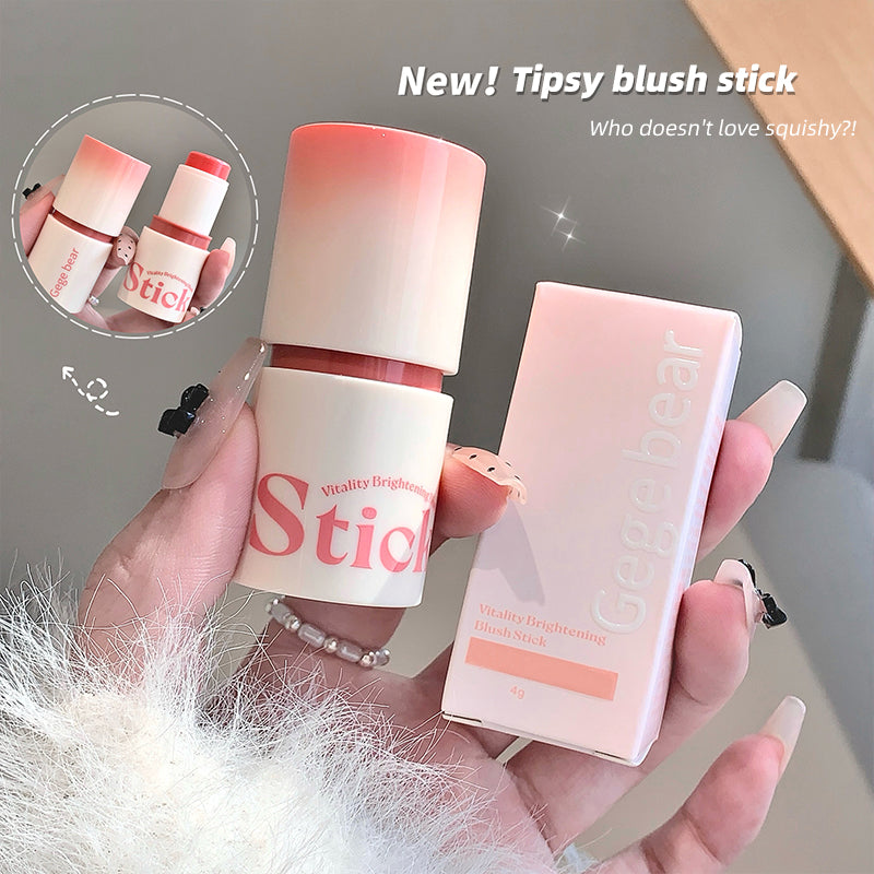 Hand holding a blush stick with packaging, labeled 'New! Tipsy blush stick', against a neutral background.