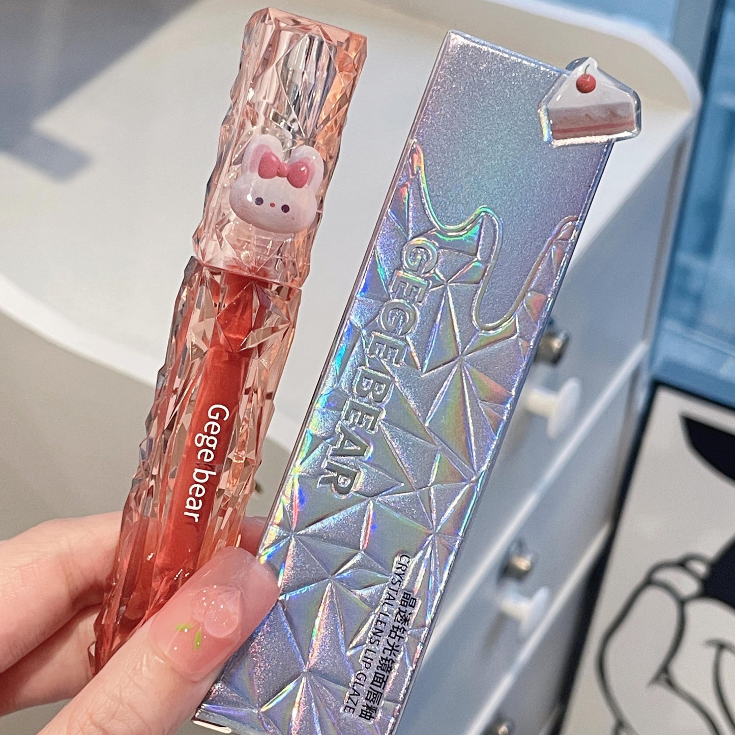 Two colorful lip products with 'Gege Bear' branding held by a hand.