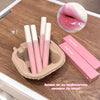 Pink lip glosses with white caps on a wooden surface, one of which is shown applied to lips.