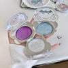 Three compact makeup cases with purple, blue, and silver contents held by a hand.