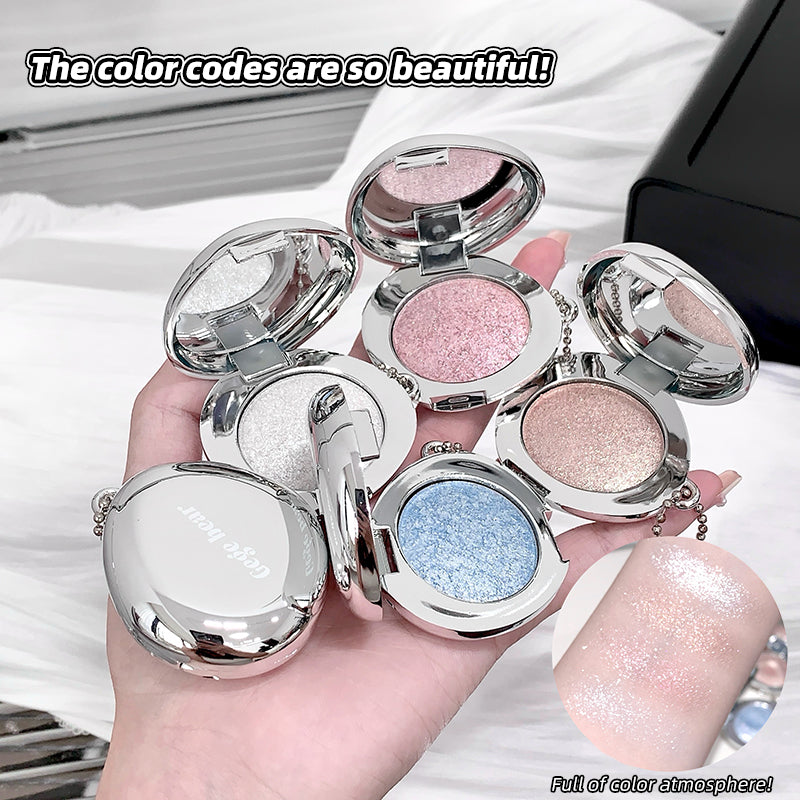 Hand holding open compact mirrors with glittery shades on a white surface