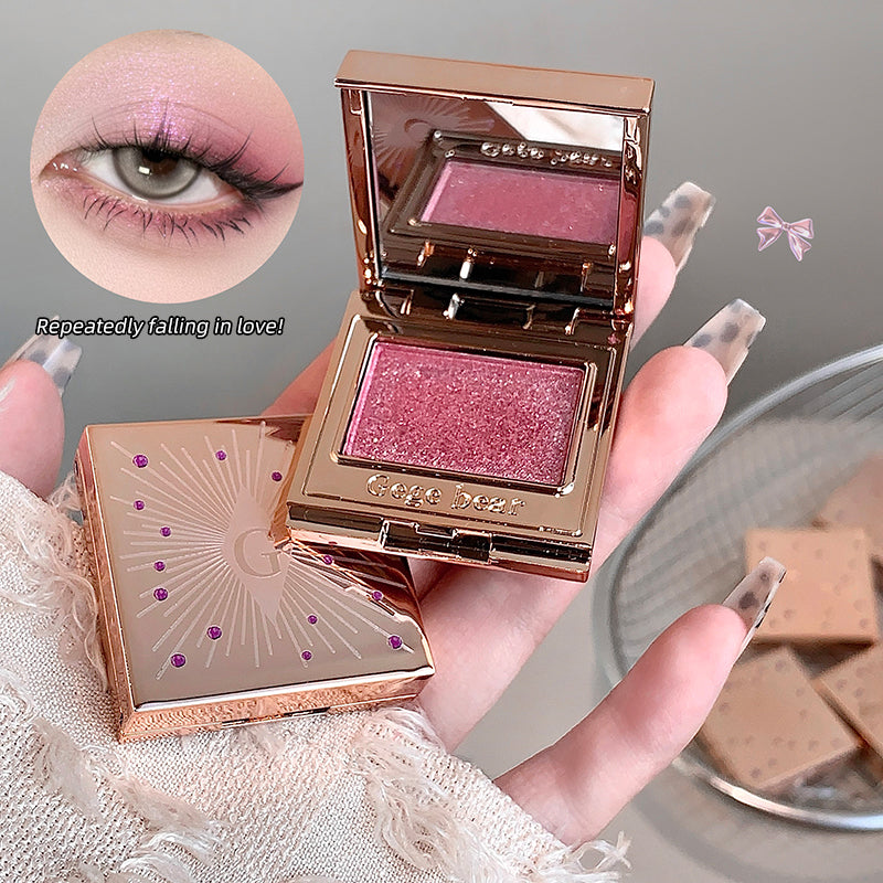 Makeup compact with pink eyeshadow held by a hand, with a close-up of an eye wearing the product.