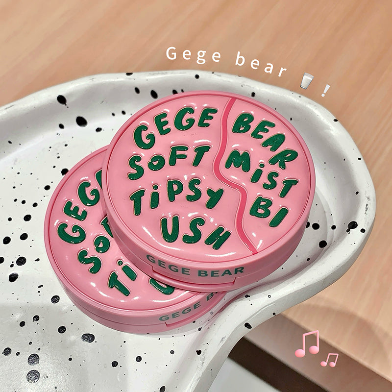 Pink and green 'Gege Bear' product on a white speckled tray with a wooden background.