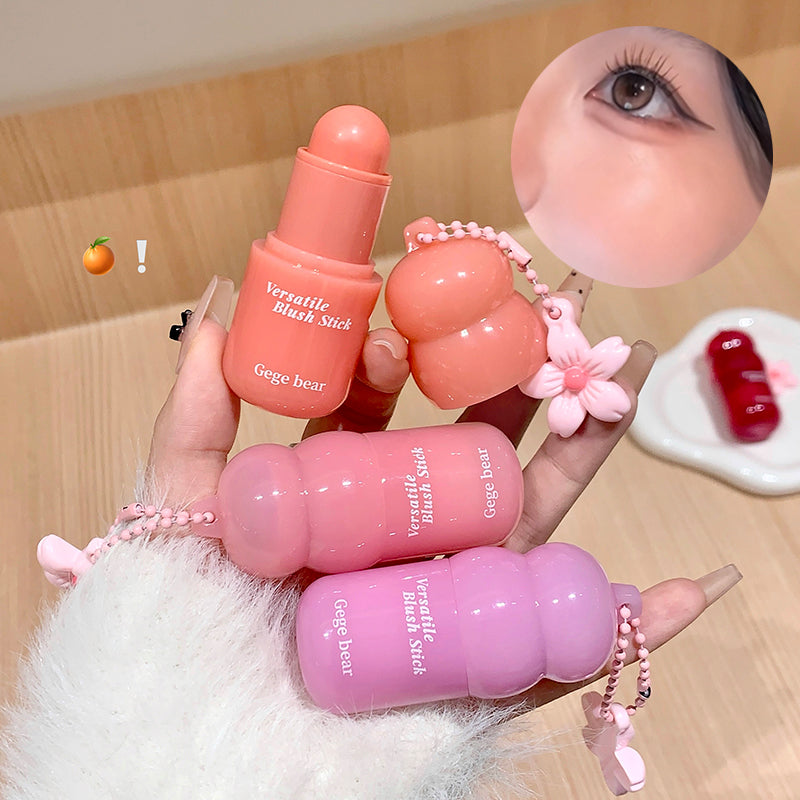 Three pink blush sticks with 'Geege bear' branding held by a hand against a wooden background.