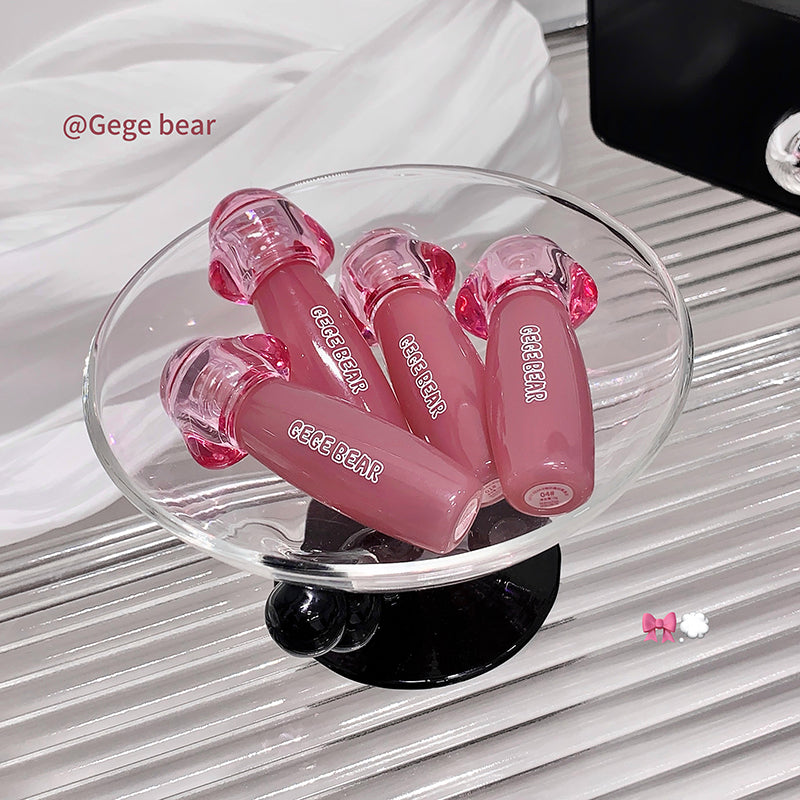 Pink lip glosses with 'Gege Bear' branding on a clear stand against a white background.