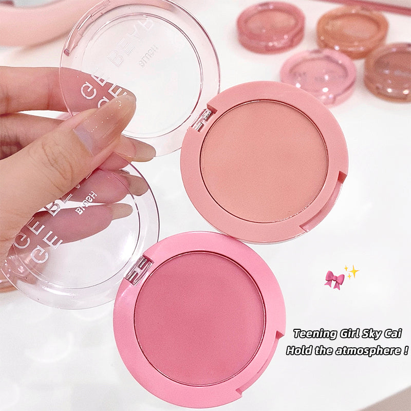 Pink blush compact with open lid showing blush color, held by a hand on a white background.