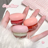 Three small jars of Gege Bear lip balm held in a hand with a soft background.
