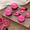 Pink makeup set with floral designs on a wooden board and beige fabric background