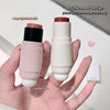 Two makeup products with a double head design held in a hand against a neutral background.