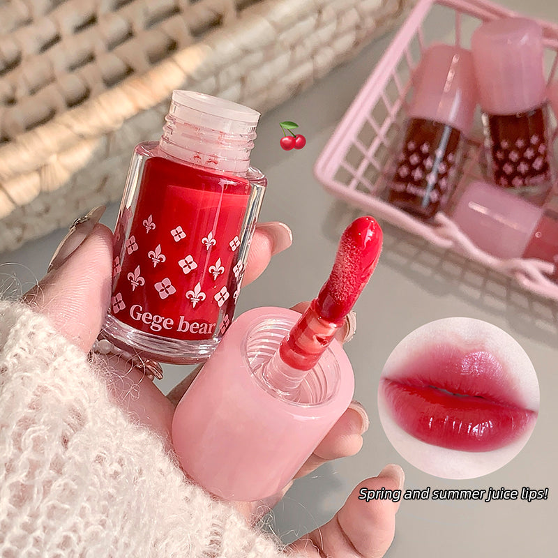 Red nail polish bottle with matching lip color, held by a hand, with a small basket of nail polishes in the background.