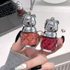 Two small bear-shaped bottles with red liquid held by a person's hand.