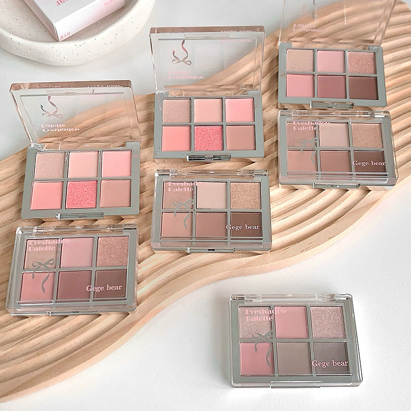 Multiple makeup palettes with pink and brown shades on a wooden surface