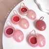 Pink lip balm containers with red lip balm inside on a white surface, branded 'Gege bear'.