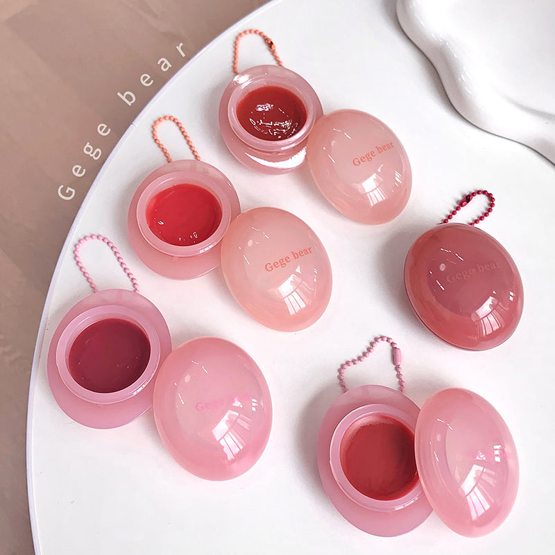 Pink lip balm containers with red lip balm inside on a white surface, branded 'Gege bear'.
