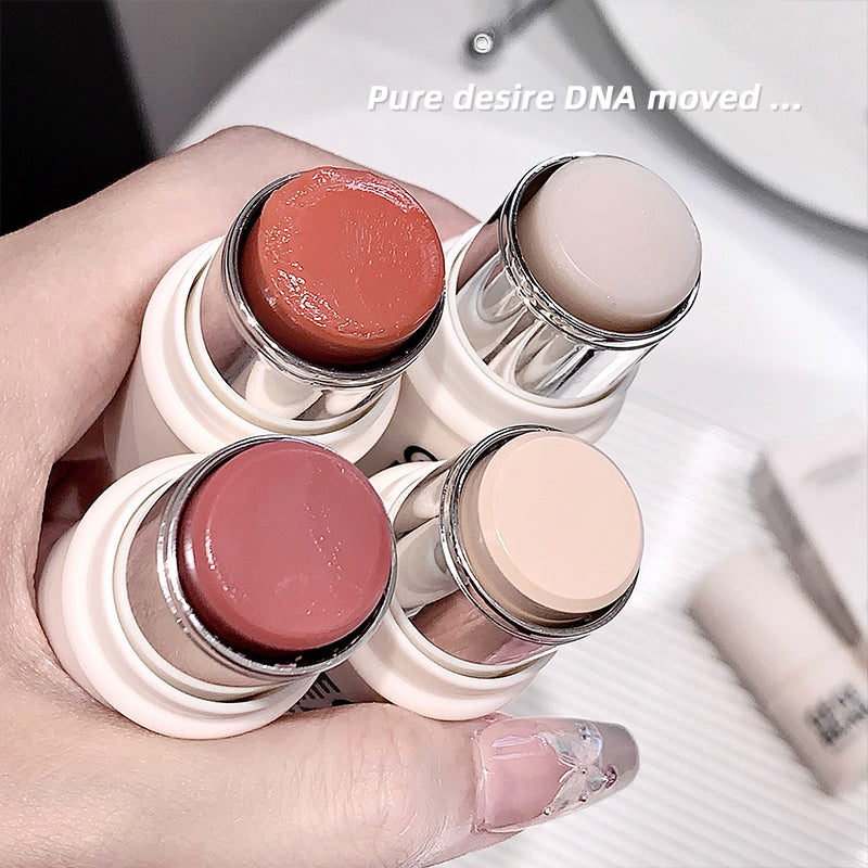 Hand holding four lipsticks with visible brand names on a white surface.
