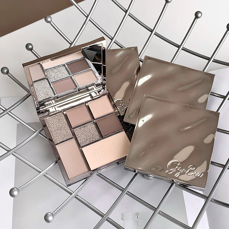 Makeup palette with open lid showing eyeshadows on a metallic grid background