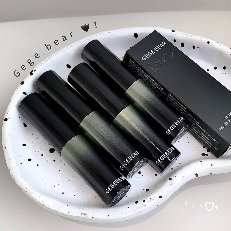 Set of black and green lip glosses with a box on a white plate, featuring 'Gege Bear' branding.