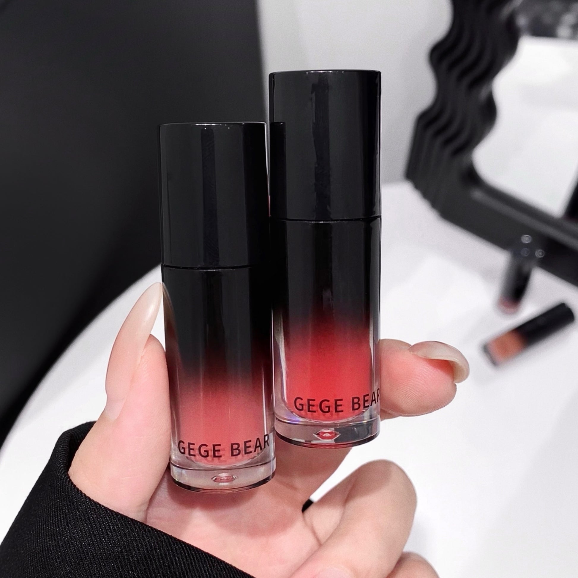 Two lip products with gradient design held by a hand, brand 'GEGE BEAR' visible.