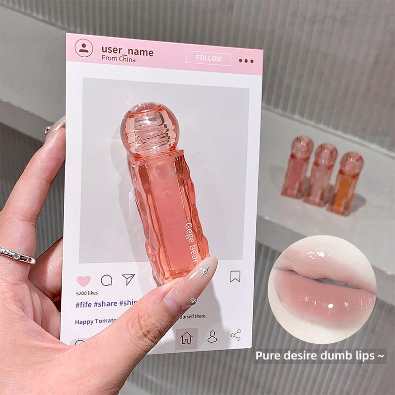 Hand holding a pink lip gloss with packaging and close-up of product on a neutral background