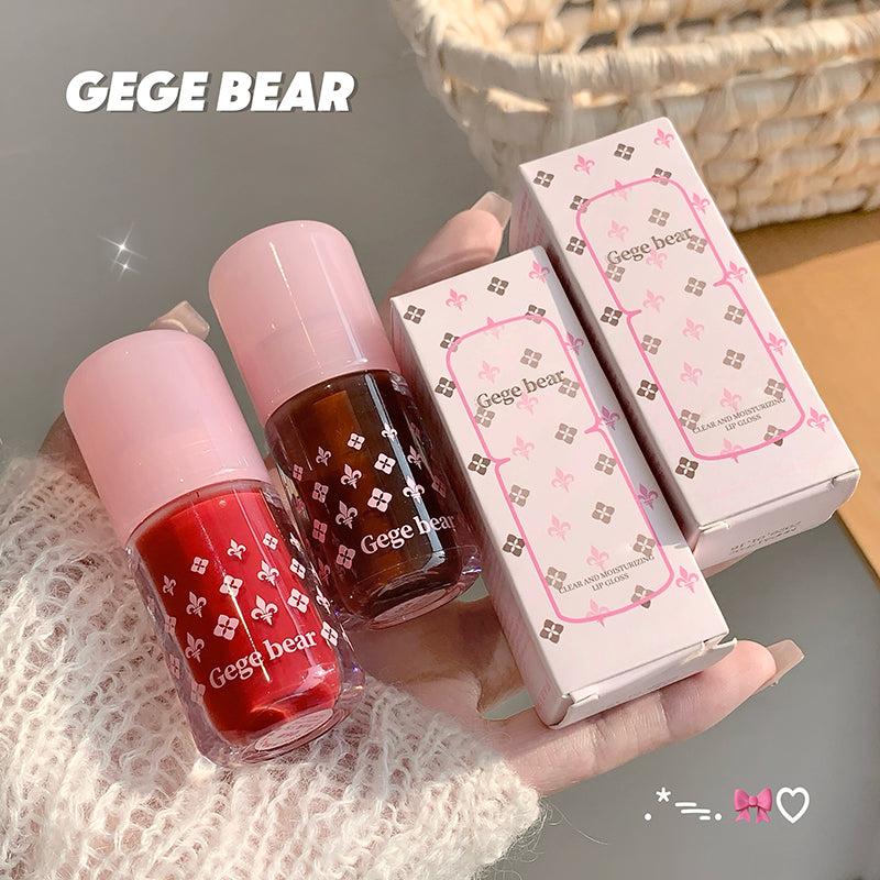 Two nail polishes with pink caps and red and brown colors, along with their packaging, held by a hand. Brand 'GEGE BEAR' is visible.