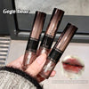 Three lip gloss tubes held by a hand with a blurred background