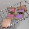 Makeup products with pink and purple shades on a metal rack.