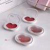 Heart-shaped blush compact with pink blush on a white surface