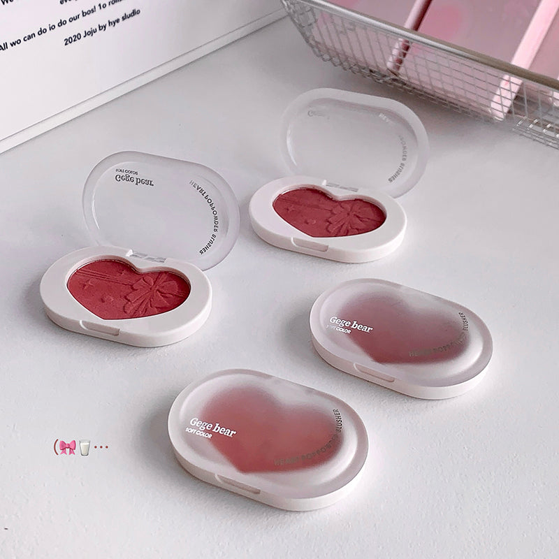 Heart-shaped blush compact with pink blush on a white surface