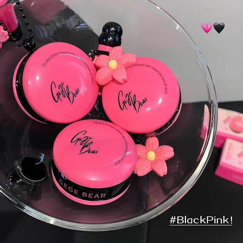 Pink makeup products with 'Gee Bear' branding on a clear glass surface, featuring '#BlackPink!' text.