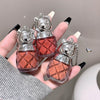 Two small red perfume bottles with silver caps held by a hand against a neutral background