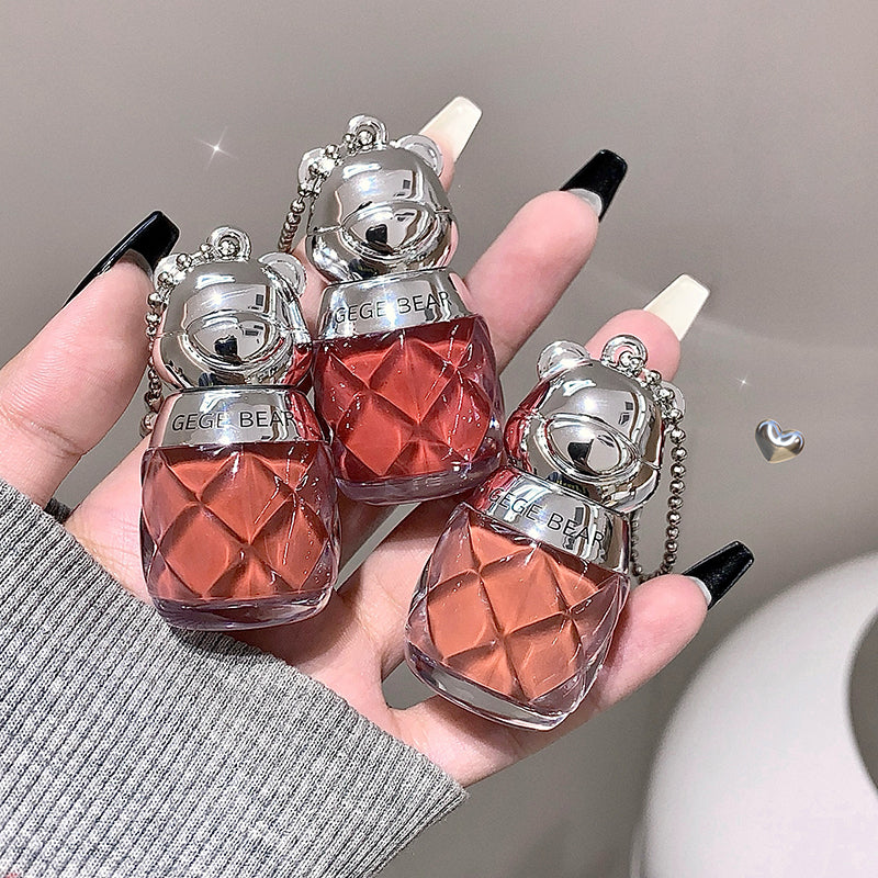 Two small red perfume bottles with silver caps held by a hand against a neutral background