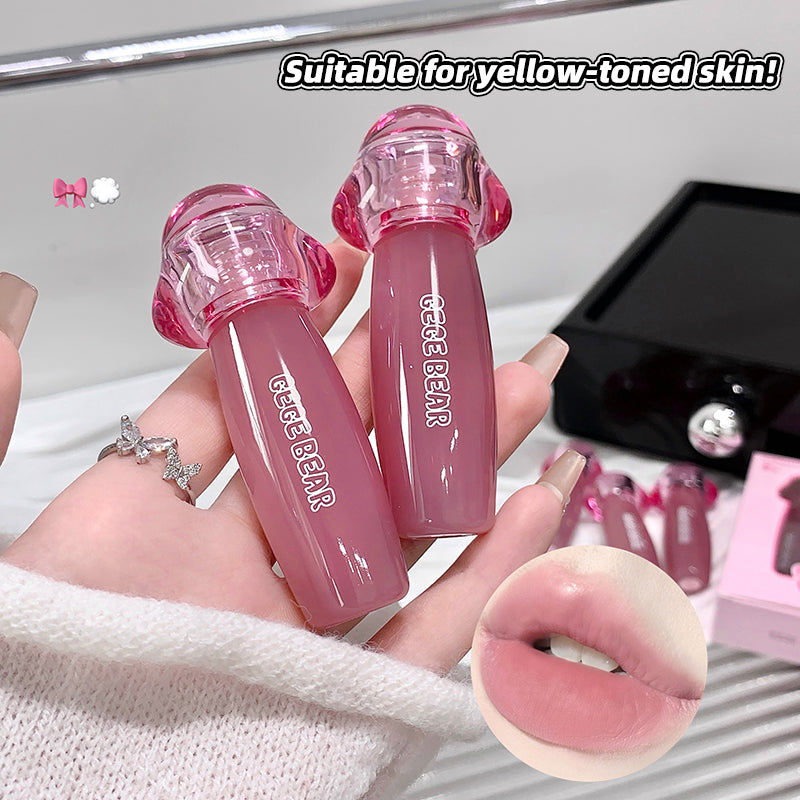 Two pink lip glosses held by a hand with a close-up of lips wearing the product, on a white background.