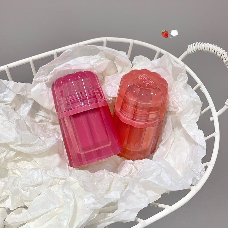 Two pink and red containers on a white textured surface with a gray background