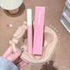 Pink lip gloss with packaging held by a hand on a textured surface, 'Gege bear' branding visible.