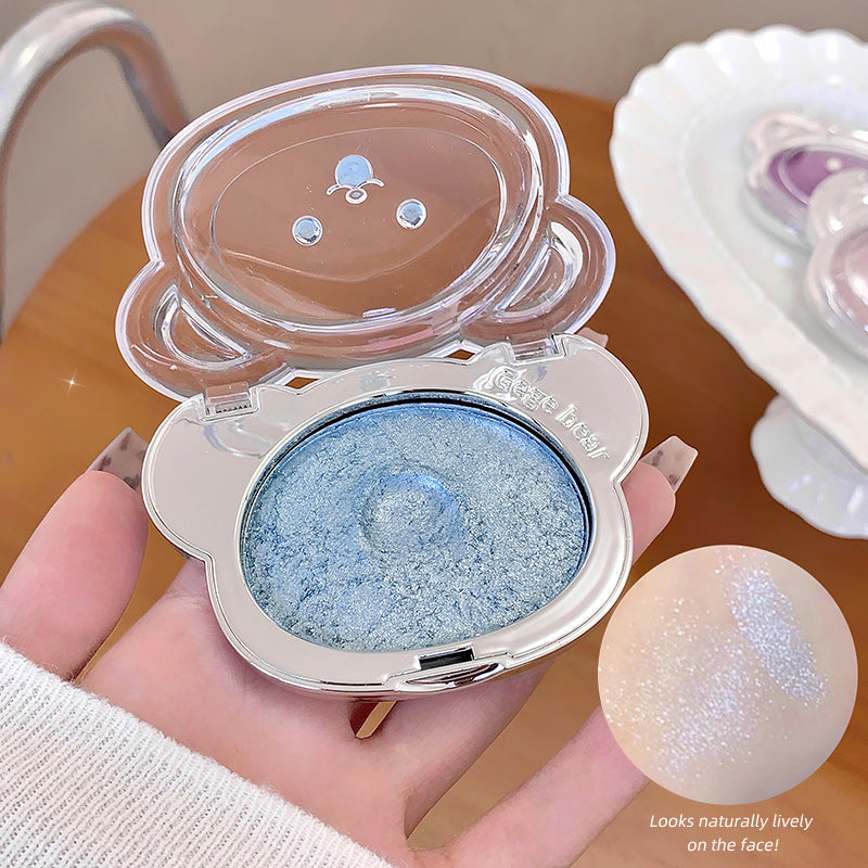 Compact mirror with blue eyeshadow and a small round mirror held by a hand.