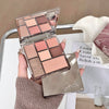 Makeup palette with multiple shades held by a hand, with a magazine in the background.