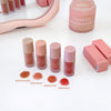 Set of lip products including lipsticks and a perfume bottle on a white surface.