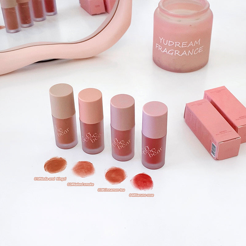 Set of lip products including lipsticks and a perfume bottle on a white surface.