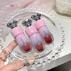 Pink lip gloss bottles with silver accents on a decorative tray