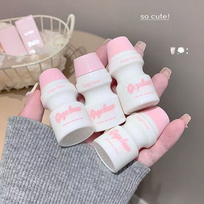 Small white bottles with pink caps held in a hand, labeled 'Cupcake'.